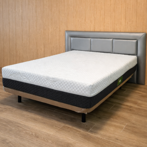 Colchón gris con acolchado superior sobre base tapizada en dormitorio con pared de madera