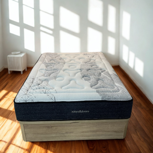 Colchón blanco y gris sobre base en dormitorio con suelo de madera y luz natural